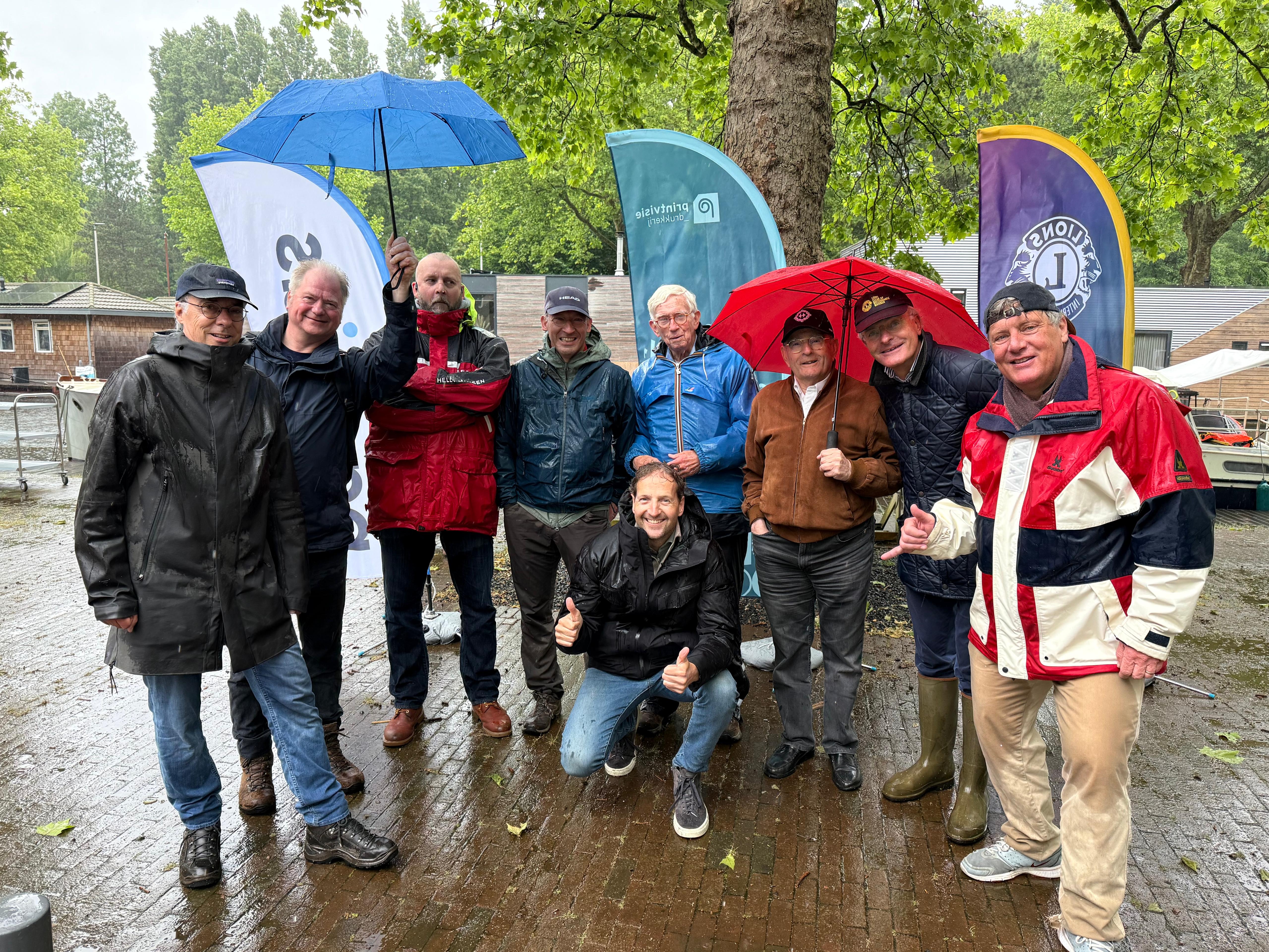 Groepsfoto in de regen met paraplu's